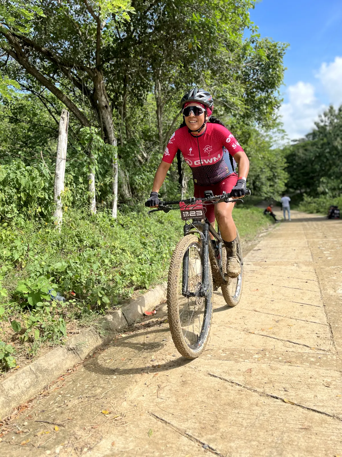 Ciclista subiendo una vía rural entre vegetación.