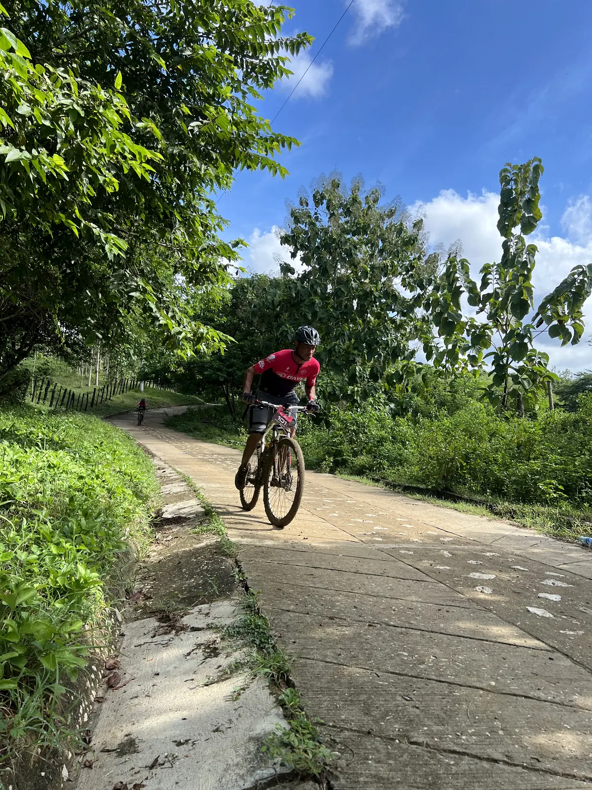Ciclista avanzando bajo cielo azul en una vía rural.